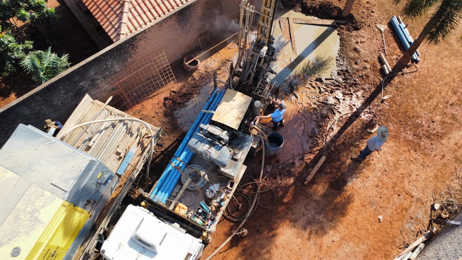 Vista aérea de canteiro de perfuração de poço artesiano com equipe e equipamentos da Renan Águas Claras em operação